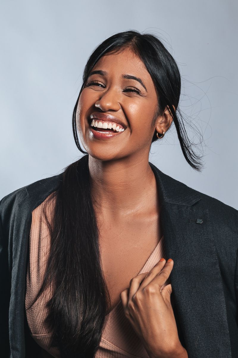 Smiling young woman in a blazer experiencing joy and confidence indoors.